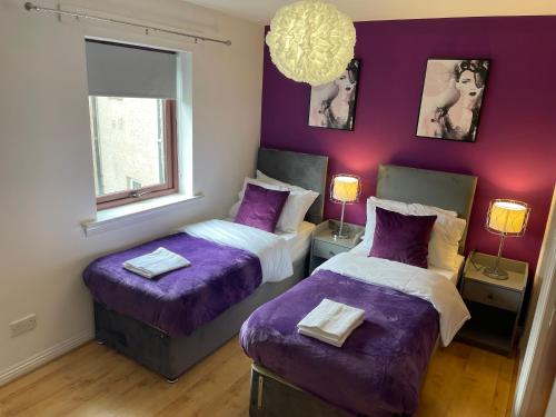 two beds in a room with purple walls at Coastal Apartment 2 Bedrooms, Sleeps upto 6, Free Parking in Prestonpans
