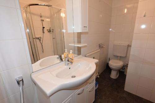 a white bathroom with a sink and a toilet at Areit Living corner top 21 in Zell am See