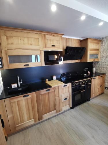 - une cuisine avec des placards en bois et une cuisinière noire dans l'établissement Duplex Les 2 Alpes avec accès direct aux pistes, à Les Deux Alpes