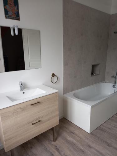 a bathroom with a white tub and a white sink at Chez Sindy et Olivier in Crèvecoeur-le-Grand