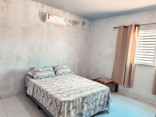 1 dormitorio con 1 cama en una habitación con ventana en Casa em Aurora do Tocantins, en Manhã