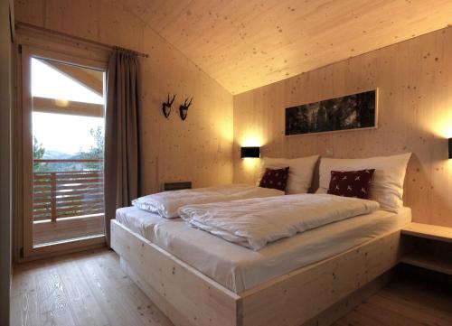 - une chambre avec un grand lit et une fenêtre dans l'établissement AlpenChalet ZirbenDuft, à Turracher Höhe