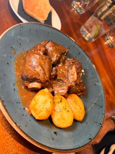 a plate of food with meat and potatoes on a table at Hotel Indigo Madrid - Gran Vía by IHG in Madrid