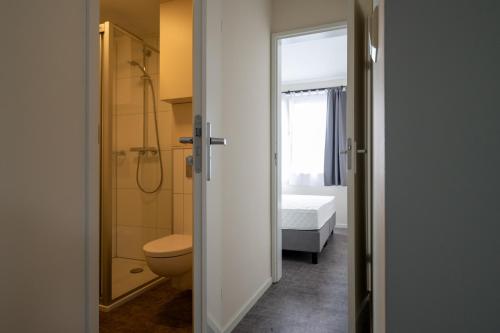 een badkamer met een toilet en een douche en een bed bij Recreatiepark Maas en Bos in Wellerlooi