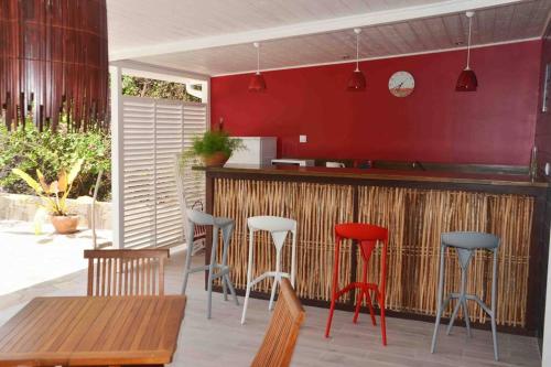 uma cozinha com um bar com paredes vermelhas e bancos em kaï colibri em Rivière-Pilote