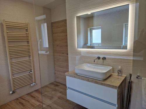 ラーシュコにあるApartmaji PR' KERINの洗面台と鏡のあるバスルーム