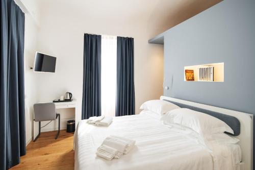 een slaapkamer met een bed met witte lakens en een bureau bij Duomo B&B in Teramo