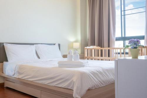 Ban SuanにあるThe Lago Apartmentsのタオルが敷かれた白いベッドのある寝室
