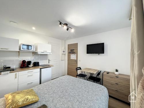 a bedroom with a bed and a kitchen with a tv at Les studios d'Elina - Entrée autonome in Châtellerault
