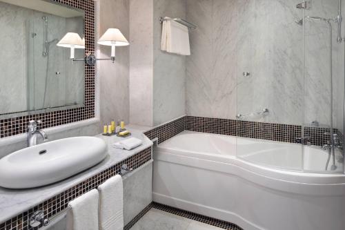 a white bathroom with a tub and a sink at Fes Marriott Hotel Jnan Palace in Fès