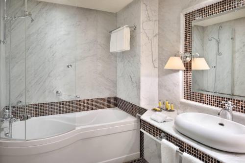 uma casa de banho com uma banheira, um lavatório e um espelho. em Fes Marriott Hotel Jnan Palace em Fez