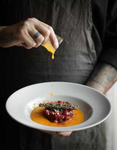 a person holding a plate with a bowl of food at Hotel & Restaurant Casolare Le Terre Rosse in San Gimignano