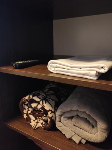 a wooden shelf with towels and a remote control on it at Rose Apartament in Brwinów