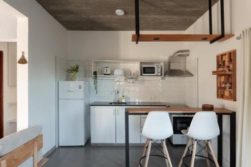 a kitchen with white appliances and two white stools at Complejo il Pensiero Punta del Diablo in Punta Del Diablo