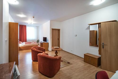a living room with two chairs and a bedroom at Hotel Spolcentrum in Svit