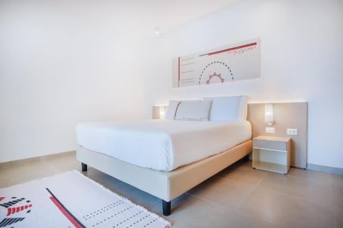 a bedroom with a white bed and a sign on the wall at Felix Hotels - Galanias Hotel & Retreat in Bari Sardo
