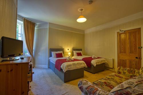 a hotel room with two beds and a tv at Woodlands Bed and Breakfast in Dornoch