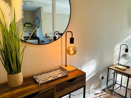 Charming Studio Apartment with Free Parking & WiFi in Milton Keynes by HP Accommodation في ميلتون كينز: طاولة تزيين مع مرآة ومصباح عليها