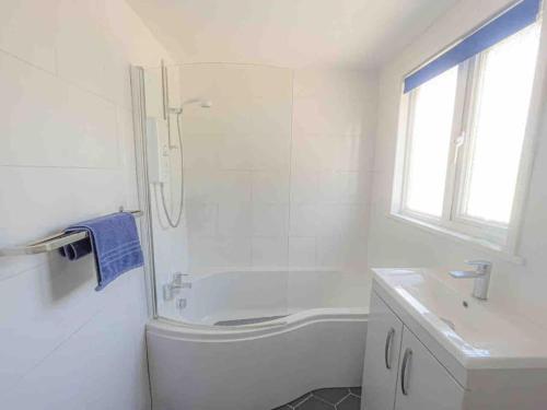 a white bathroom with a shower and a sink at Crud Yr Awel, Dinas, Pembrokeshire in Dinas