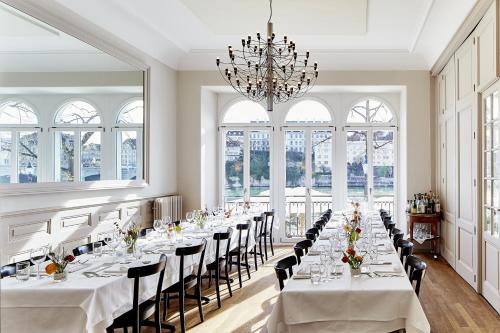une grande salle à manger avec des tables et des chaises blanches dans l'établissement Krafft Basel, à Bâle