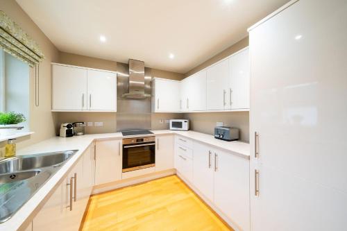 a kitchen with white cabinets and a sink at Strathallan - Luxury 3 Bedroom Apartment, Gleneagles, Auchterarder in Auchterarder