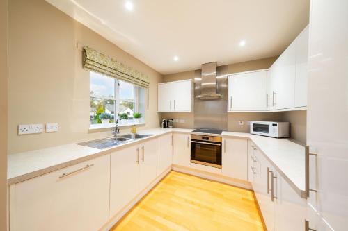 a kitchen with white cabinets and a window at Strathallan - Luxury 3 Bedroom Apartment, Gleneagles, Auchterarder in Auchterarder