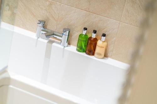 three bottles of alcohol sitting on a bathroom sink at Strathallan - Luxury 3 Bedroom Apartment, Gleneagles, Auchterarder in Auchterarder