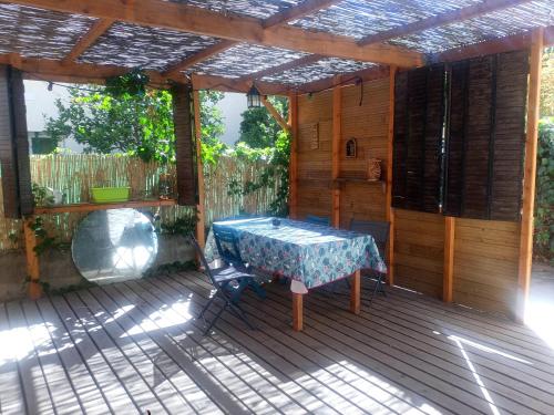 eine Terrasse mit einem Tisch auf einer Holzterrasse in der Unterkunft Studio d'aqui et d'ailleurs in Perpignan