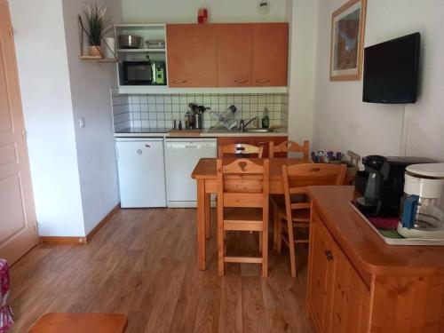 une cuisine avec des armoires en bois et une table et des chaises dans l'établissement T2 au pied des pistes, à Puy-Saint-Vincent