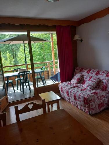un salon avec un canapé et une terrasse avec une table dans l'établissement T2 au pied des pistes, à Puy-Saint-Vincent