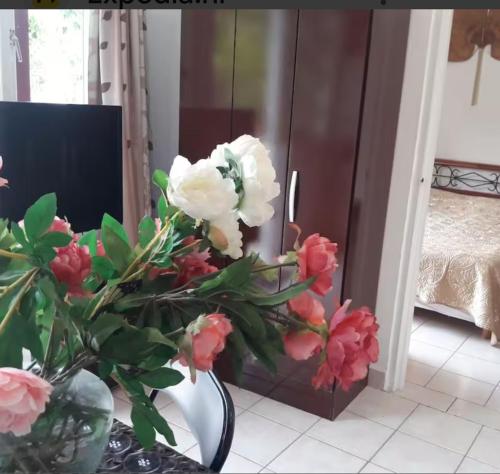 a vase with pink and white flowers in a room at YOUR FIRST DAY Hotel on Aruba in Oranjestad