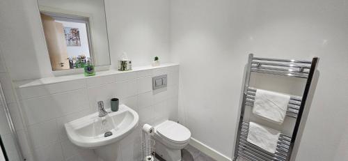 a white bathroom with a sink and a toilet at Whiterose Roundabout Apartment in Doncaster