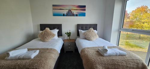 two twin beds in a room with a window at Whiterose Roundabout Apartment in Doncaster