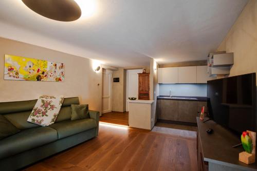 a living room with a green couch and a kitchen at La Noix - Alloggi ad uso turistico - VDA - ARVIER - n 0041 e n 0042 in Arvier