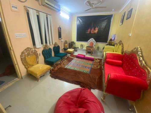 a living room with a red couch and chairs at Mahavatar Babaji Farm Stay in Bangalore