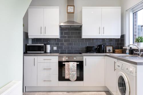 a kitchen with white cabinets and a dishwasher at Fully Refurbished North Belfast Home 2 in Belfast