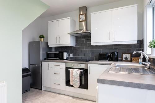 a kitchen with white cabinets and a stainless steel refrigerator at Fully Refurbished North Belfast Home 2 in Belfast