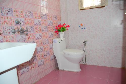 a bathroom with a toilet with a vase of flowers on it at River Stay - Homestay by Wanderlust Rural Tourism in Dehradun