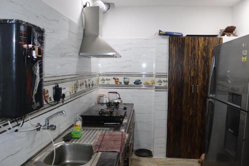 cocina con fregadero y nevera negra en Royal Experience Marhaba Villa Nest, en Mahabalipuram