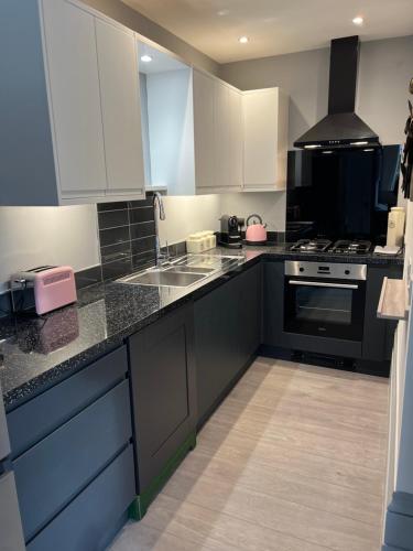 a kitchen with black and white counters and appliances at Luxury garden flat under the Castle in Kent