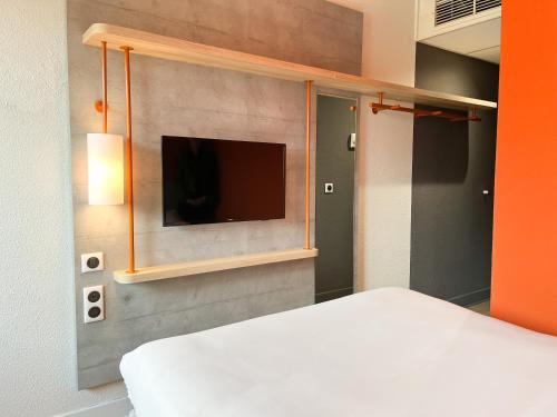 een slaapkamer met een bed en een tv aan de muur bij Ibis Budget Saint Christol Les Alès in Saint-Christol-lès-Alès