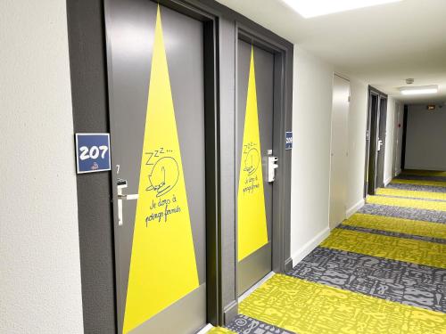 a hallway with doors with yellow signs on them at Ibis Budget Saint Christol Les Alès in Saint-Christol-lès-Alès