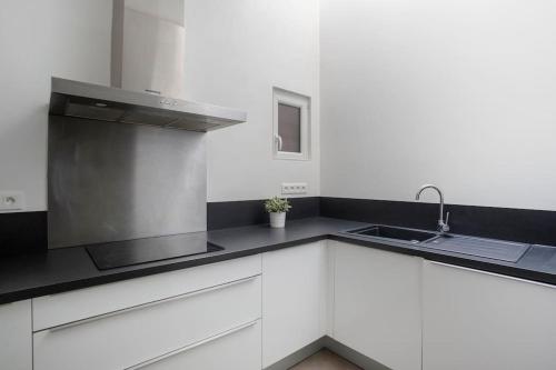 a kitchen with white cabinets and a sink at Saint Thomas 2 - Joli T2 dans Strasbourg in Strasbourg