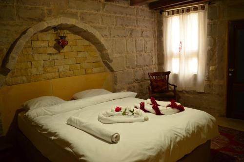 ein Bett mit weißer Bettwäsche und roten Blumen darauf in der Unterkunft Mozaik Stone Hotel in Avanos