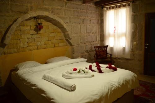 アヴァノスにあるMozaik Stone Hotelの白いシーツと赤い花が飾られたベッド