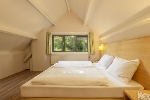 a large white bed in a room with a window at Center Parcs Limburgse Peel Limburg-Brabant in America