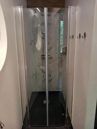 een douche met een glazen deur in de badkamer bij Ruim appartement voor 14 personen in Eijsden