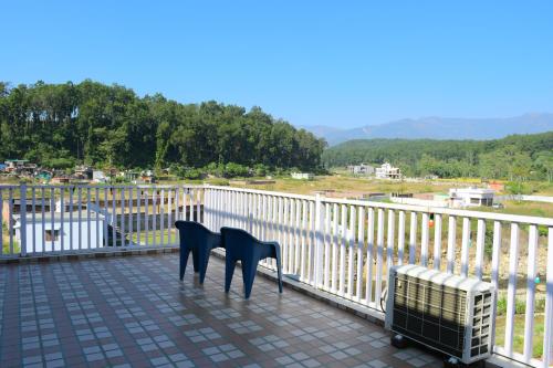 two chairs sitting on a balcony looking out at the water at River Stay - Homestay by Wanderlust Rural Tourism in Dehradun