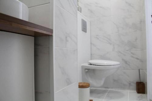 a white bathroom with a toilet and marble walls at Cocon Perret - Plage du Havre - Design & Moderne in Le Havre