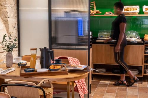a woman standing in a kitchen preparing food at Alberte Hôtel in Paris